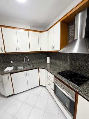 A kitchen with white cabinets, a granite countertop, stainless steel appliances, and a built-in oven.