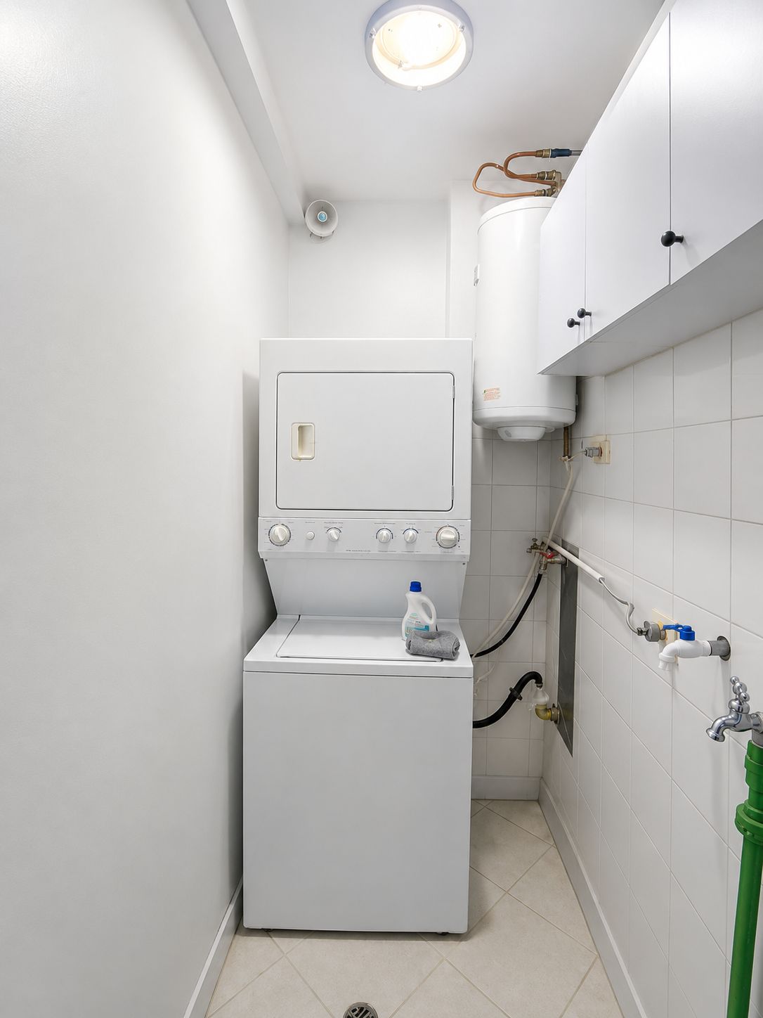 Une petite buanderie équipée d’un lave-linge, d’un sèche-linge et d’un chauffe-eau.