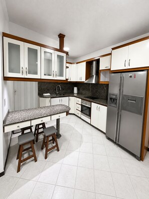 Una cocina moderna con armarios blancos, un refrigerador de acero inoxidable y una encimera de granito.