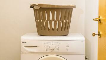 A front-loading washing machine with a beige basket on top.