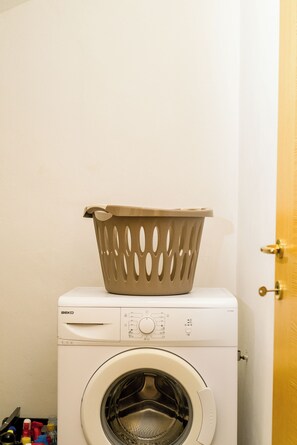 A front-loading washing machine with a beige basket on top.