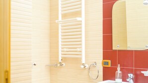 Un baño con bañera, lavamanos, toallero y espejo.