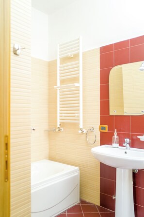 Une salle de bain avec une baignoire, un lavabo, un porte-serviettes et un miroir.