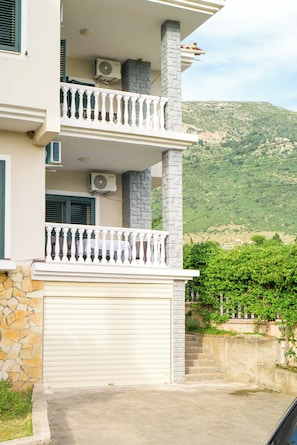 A two-story building with a stone facade, a balcony with white balustrades, and a garage door.