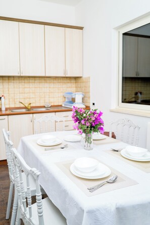A dining area with a table set for four, white chairs, and a vase with flowers.