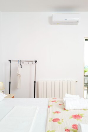 Une chambre avec un lit, un radiateur, un portant à vêtements et un appareil de climatisation.