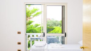 Un dormitorio con cama, ventana y vista a espacios verdes.