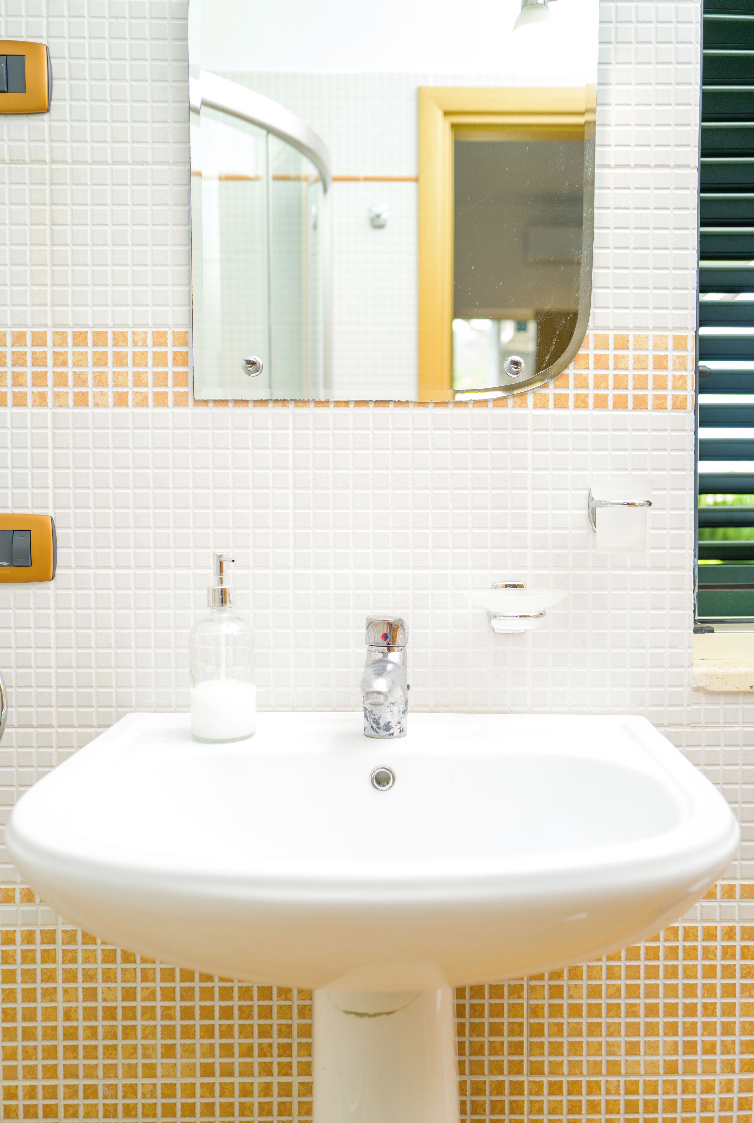 A bathroom with a white sink, a mirror, and a towel rack.