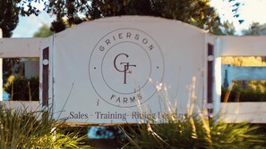 Placa de Grierson Farms com logotipo e texto indicando vendas, treinamento e aulas de equitação.