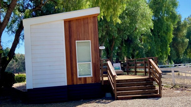 A small wooden cabin with a white exterior, a single door, and a window. There is a wooden staircase leading up to the cabin. - "The Office" - located the beautiful wine & horse country of Santa Barbara (Santa Ynez)