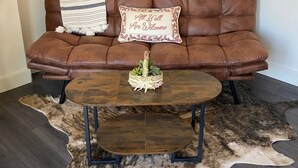 A brown leather sofa with a cushion, a small round wooden table, and a cowhide rug. - "The Office" - located the beautiful wine & horse country of Santa Barbara (Santa Ynez)