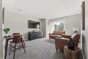 Un salon comprenant un canapé, un téléviseur, une table à manger avec des chaises et un vase décoratif.