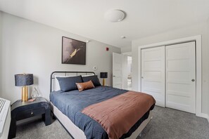 Une chambre à coucher avec un lit, des tables de chevet, une lampe, un tableau et une armoire.
