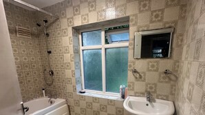 A bathroom with a bathtub, a sink, and a window. - Stylish 4-Bed Detached Home Close to Grantham Town & Amenities (Grantham)