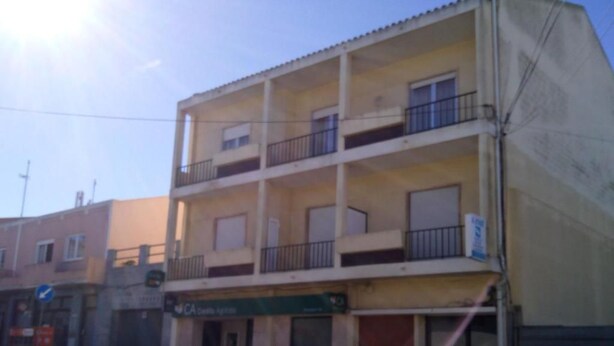 Un edificio a più piani con balconi, un ingresso al piano terra ben visibile e un'auto parcheggiata.