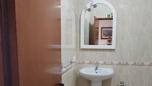 Un baño con puerta de madera, un espejo grande, dos lavamanos y un tapete negro en el suelo.