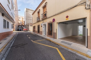 A narrow street with parked cars, a building with a garage, and a no-parking sign. - Casa Augusto - next to the Roman Theater, with a garage (Mérida)