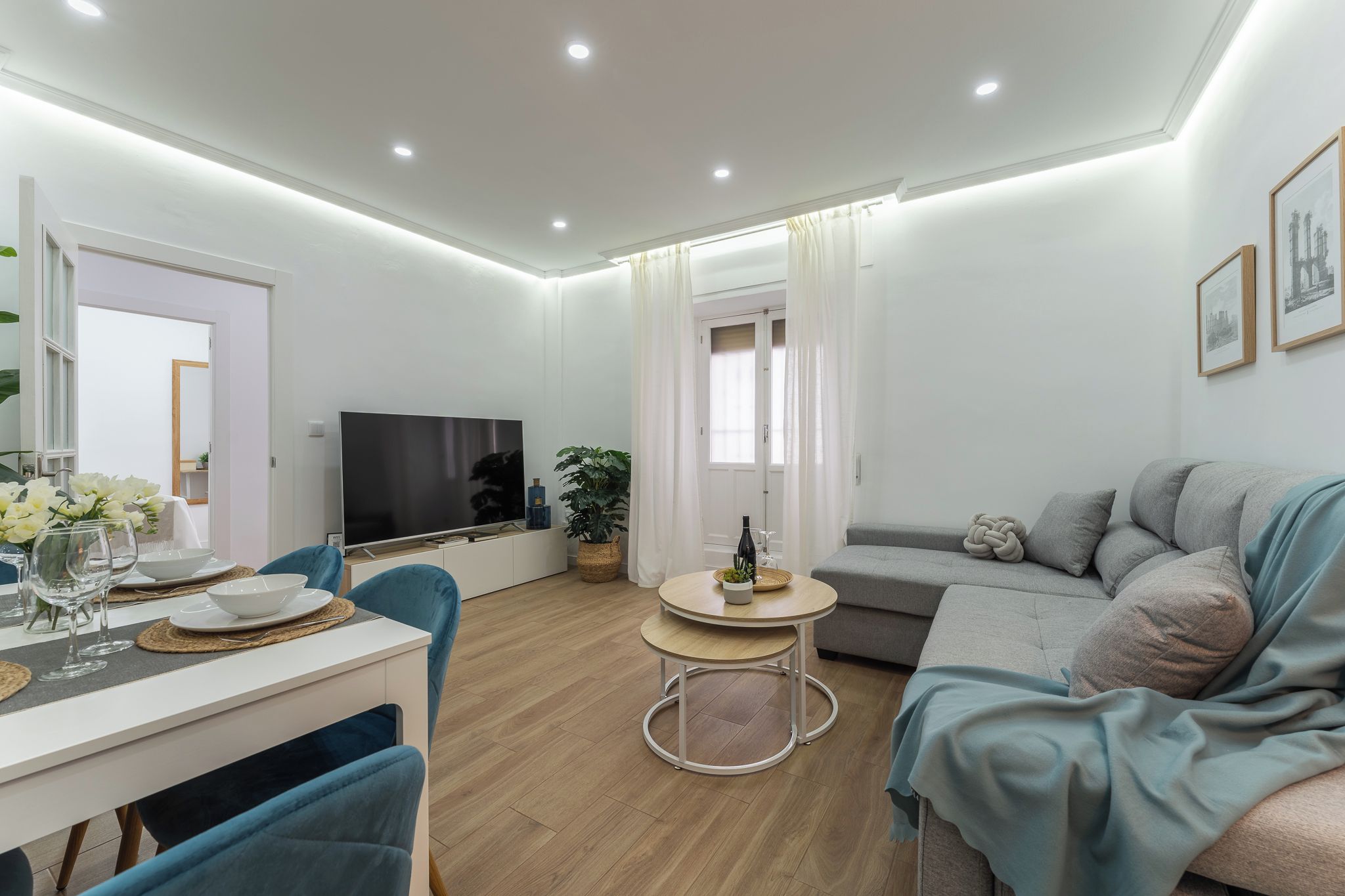 Een moderne woonkamer met een eethoek, een flatscreen televisie en een bank.