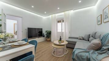 Een moderne woonkamer met een eethoek, een flatscreen televisie en een bank.