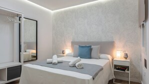 A modern bedroom with a large bed, bedside tables, a mirror, and a ceiling light. - Casa Augusto - next to the Roman Theater, with a garage (Mérida)