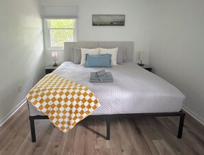 A neatly made bed with a checkered blanket, a headboard, and two bedside lamps.