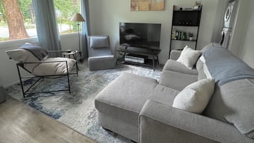 Un soggiorno moderno con un divano grigio, un mobile TV nero, un tavolino e una libreria.