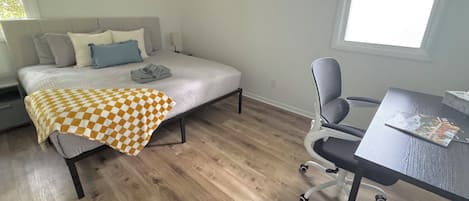 A bedroom with a bed, a desk, and a chair.