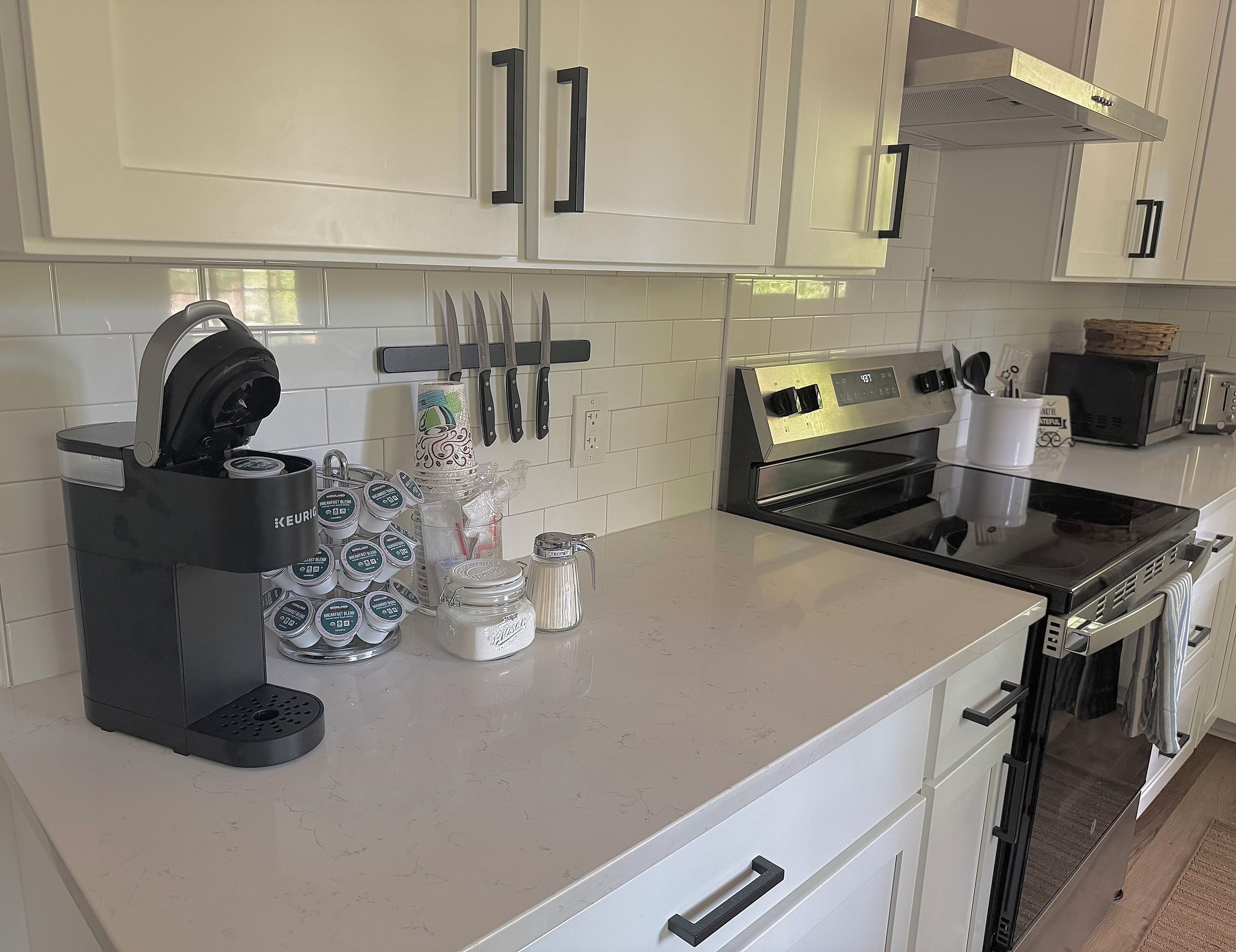 Una cucina con mobili bianchi, una macchina da caffè, un forno a microonde e un tostapane.