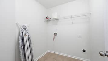 A small, white-walled room with a door, a radiator, and a shelf with a box on it.