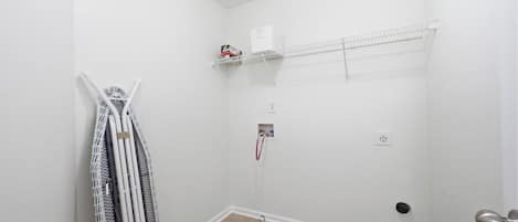 A small, white-walled room with a door, a radiator, and a shelf with a box on it.