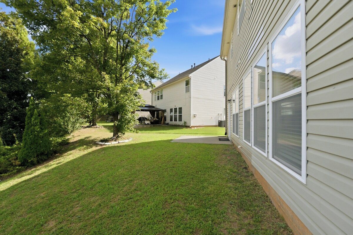 A residential property with a well-maintained lawn, a covered patio, and a house with a siding exterior.