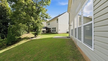 A residential property with a well-maintained lawn, a covered patio, and a house with a siding exterior.