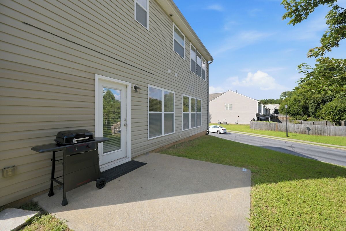 A residential exterior with a sliding glass door, a small patio area, and a vehicle parked in the driveway.