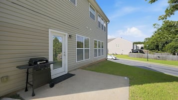 A residential exterior with a sliding glass door, a small patio area, and a vehicle parked in the driveway.