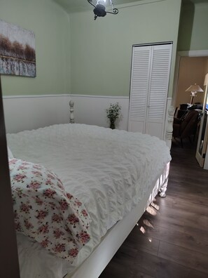 Ein Schlafzimmer mit einem großen Bett, einem Nachttisch, einer Lampe, einem Sessel und einem Kleiderschrank.
