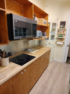 A kitchen with wooden cabinets, a microwave, a toaster, and a wooden countertop. - La Finca 1928 w stream in Valley of Moon/Historical 1 Bd 2Bath two-level cabin (Crestline)