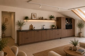 Una cocina moderna con armarios de madera, horno empotrado y encimera con plantas.