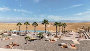 A resort with outdoor seating, palm trees, and a pool.