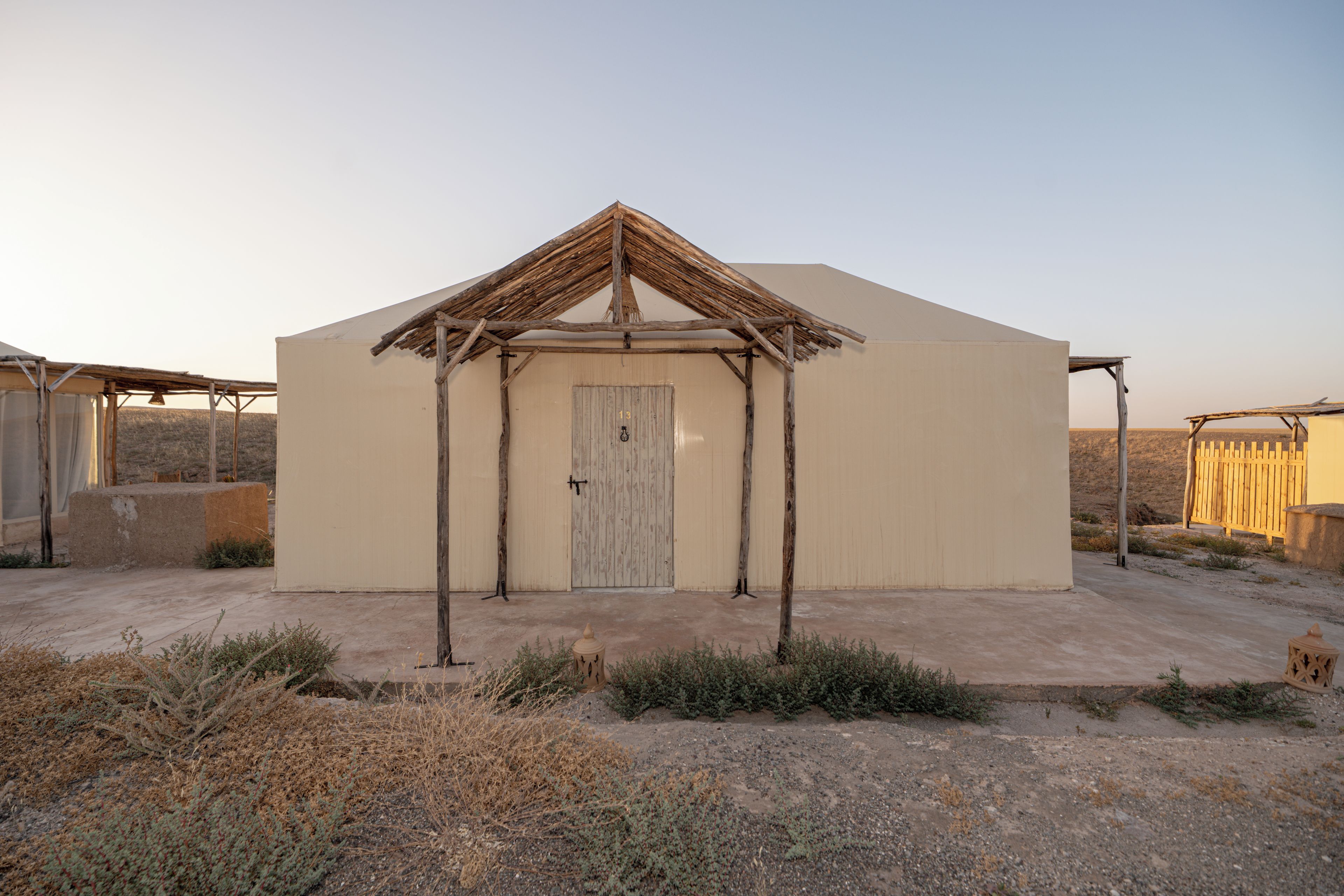 Un edificio de una sola planta con un diseño sencillo y rústico, que presenta una puerta de madera y una estructura de techo de paja.
