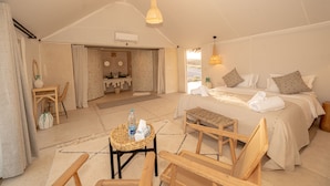 A spacious tent-style room with a bed, seating area, and a bathroom.