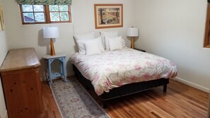 A bedroom with a bed, two bedside lamps, a nightstand, a dresser, a window with a view, and a framed picture on the wall. - Cozy 2-bedroom house for adventuring throughout the Roaring Fork Valley (Snowmass)