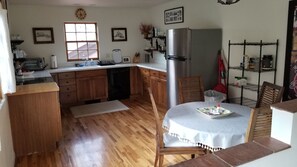 A kitchen with wooden cabinets, a stainless steel refrigerator, a dining table with chairs, and a window. - Cozy 2-bedroom house for adventuring throughout the Roaring Fork Valley (Snowmass)