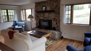 A living room with a stone fireplace, a sofa, a coffee table, and two armchairs. - Cozy 2-bedroom house for adventuring throughout the Roaring Fork Valley (Snowmass)