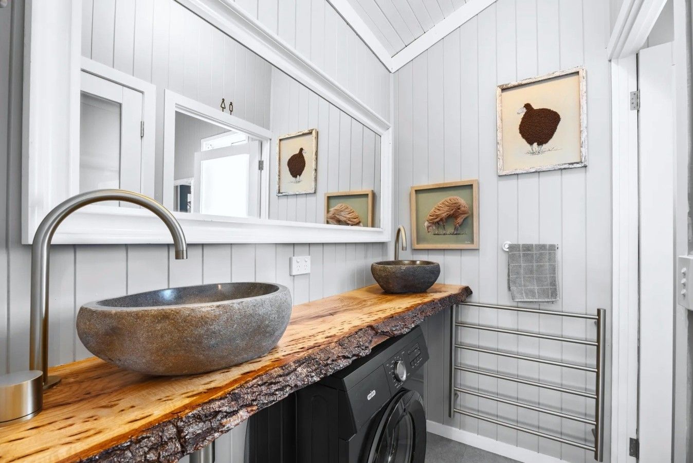 A modern bathroom with a stone sink, wooden countertop, and a large mirror.