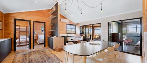 A modern interior with a dining area, kitchen, and a bedroom with bunk beds.