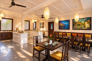 Zona de dinning d'un hotel amb una illa central, diferents disposicions de seients i obres d'art a les parets.