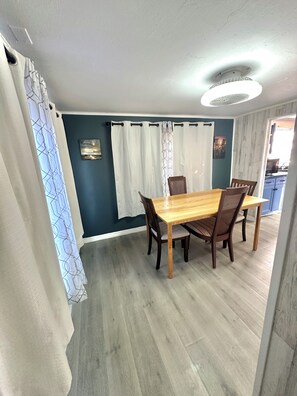 A dining area with a wooden table and chairs, a ceiling light, and a view into another room. - Lovely 3-bedroom house with AC in North Fort Myers pet friendly (North Fort Myers)