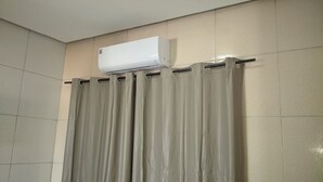 Een badkamer met douchegordijn, een wandairconditioner en betegelde wanden.