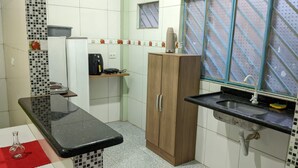 Een keuken met een zwart aanrecht, een houten kast, een spoelbak en een magnetron.