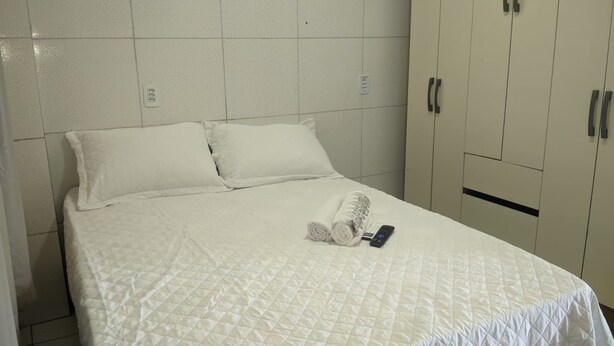 Een hotelkamer met een bed, handdoeken en een afstandsbediening.